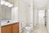 Bright and inviting bathroom featuring modern vanity, elegant lighting, and sleek tile flooring in a spacious apartment.