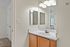 Bright bathroom with elegant lighting, sleek mirror, and modern vanity, offering a serene and welcoming atmosphere.
