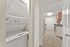Modern apartment featuring a sleek in-unit washer and dryer adjacent to a stylish kitchen with granite countertops and wood cabinetry.