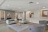 Modern living room with sleek gray sofa, abstract art, and elegant glass coffee table.