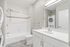 Modern bathroom showcasing sleek fixtures, integrated laundry setup, and elegant tile accents with a cozy bathtub.