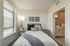 Cozy bedroom with elegant decor, featuring a comfortable bed, stylish artwork, and an ensuite bathroom filled with natural light.