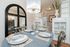 Elegant dining area with a chic chandelier, mirrored wall, and stylish table setting in a cozy apartment.