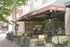 Charming sidewalk cafe with vibrant outdoor seating, inviting atmosphere under a shaded awning.