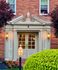 Charming brick building entrance with elegant lanterns and lush landscaping, exuding classic architectural style.