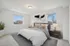 Inviting bedroom with a plush bed, modern decor, and natural light from large windows.