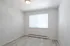 Bright and airy empty room with modern light fixture, large window, and elegant light wood flooring.