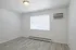 Bright and airy room with modern light fixture, large window, and efficient wall-mounted air conditioning unit.