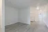 Bright and inviting apartment interior showcasing modern white walls, sleek laminate flooring, and a compact kitchen with ample storage space.