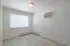 Bright room with large window, sleek laminate flooring, and air conditioning unit, perfect for a cozy urban apartment.