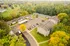 Scenic aerial view of an apartment complex surrounded by vibrant green and yellow autumn trees, featuring a central parking area and spacious grassy lawns.