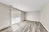 Bright and spacious room with sleek laminate flooring and large sliding glass doors leading to a sunny outdoor area.