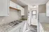 Bright and modern kitchen with white cabinetry, sleek countertops, and a window providing natural light.