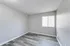 Bright and airy room with sleek gray flooring and ample natural light from a wide window, offering a versatile space for personalization.