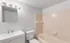Bright and welcoming bathroom featuring elegant tilework, a spacious bathtub, sleek vanity with modern fixtures, and ample lighting.