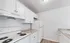 Bright and modern kitchen featuring sleek white cabinetry, a spacious refrigerator, and a pristine oven with a granite countertop.