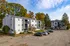 Charming apartment complex nestled among vibrant autumn trees, featuring spacious balconies and ample parking, under a clear blue sky.