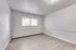 Bright, empty room with fresh gray walls and modern laminate flooring, featuring a large window for natural light.