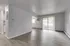 Bright and airy apartment interior showcasing open living space with sleek flooring and large sliding doors leading to a charming outdoor view.