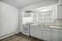 Bright and airy kitchen with modern white cabinetry, sleek countertops, and ample natural light through large window.