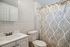 Chic bathroom with modern fixtures, elegant white tiles, and a stylish patterned shower curtain.