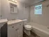 Bright and modern bathroom featuring a sleek vanity, elegant tiled walls, and a luxurious bathtub, perfect for relaxation.