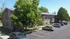 Charming brick apartment complex surrounded by lush greenery, featuring convenient parking spaces under a clear blue sky.