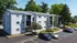 Charming apartment complex with modern design, nestled among lush trees, featuring ample parking and serene surroundings.