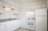 Bright, modern kitchen with sleek white cabinetry and granite countertops, featuring a spacious fridge and electric stove.