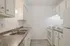 Modern kitchen with sleek granite countertops, white cabinetry, and stainless steel double sink, offering a bright and functional cooking space.