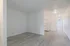 Bright, open-concept apartment space with modern light wood flooring, featuring a cozy kitchen area with crisp white cabinetry and appliances.
