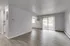 Bright and spacious living room with modern flooring and large sliding glass door leading to outdoor view.