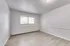 Bright and spacious empty room with large window, elegant light gray walls, and stylish wood flooring.