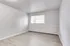 Bright, minimalist room with large window, stylish wood floors, and fresh neutral walls; ideal for a cozy and personal touch.