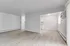 Inviting open-concept living area with light wood flooring and modern finishes, leading into a cozy kitchen space.
