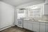 Bright and modern kitchen with sleek white cabinets, stainless steel appliances, and large windows offering ample natural light.