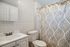 Charming bathroom featuring a sleek sink, modern fixtures, and an elegant shower curtain with leaf patterns.