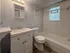 Bright modern bathroom featuring a sleek vanity with mirror, pristine bathtub, and stylish glass block window allowing natural light.