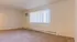 Bright and spacious living room with large window and soft carpeting, ideal for relaxation.