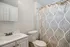 Bright and inviting bathroom with elegant patterned shower curtain, pristine vanity sink, and polished fixtures.