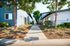 Charming apartment complex with a picturesque walkway surrounded by lush greenery and vibrant flowers.