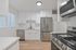Modern kitchen with sleek stainless steel appliances, bright white cabinetry, and elegant hardwood floors.