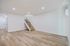 Modern open-space apartment with sleek wooden floors, elegant staircase, and bright lighting.