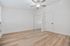 Bright and airy bedroom with elegant light wood flooring, mirrored closet doors, and a stylish ceiling fan.