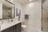 Elegant bathroom with modern fixtures, large mirror, and sleek glass-enclosed shower, perfect for a luxurious apartment experience.
