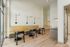 Modern community workspace with stylish wall lighting, cozy wood tables, and sleek seating, complemented by large windows for ample natural light.