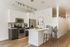 Sleek modern kitchen with stainless steel appliances, bright white finishes, and a chic breakfast bar with seating.