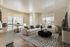 Bright and modern living room featuring elegant white sofas, a chic black coffee table, and large windows showcasing a city view.