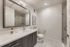 Elegant and modern bathroom with sleek vanity, large mirror, and glass-enclosed shower, showcasing contemporary design and luxury finishes.