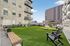 Modern apartment community with a vibrant outdoor communal area, featuring comfortable seating, cornhole games, and lush green artificial turf.